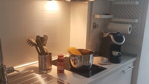 A modern kitchen with white cabinets, stainless steel appliances, and a pot on the stove. - Appartamento Gradisca (Lecco)