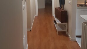 A narrow hallway with a wooden floor, a white door, a white ceiling light, a white radiator, and a white sink. - Appartamento Gradisca (Lecco)