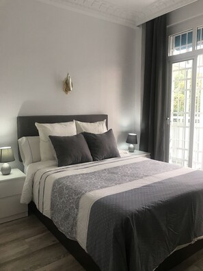 Un letto rifatto con cura, una coperta a motivi decorativi, due abat-jour e un elemento decorativo a parete.