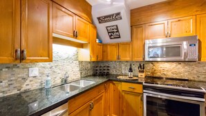 A kitchen with wooden cabinets, a stainless steel microwave, and a wine rack.