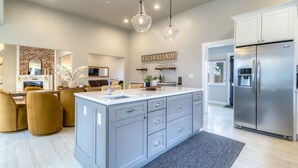 Una cucina moderna con isola centrale, elettrodomestici in acciaio inossidabile e illuminazione a sospensione.