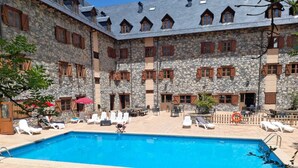 Ein Steinhaus mit Pool, Sitzgelegenheiten im Freien und einem eingezäunten Patio.