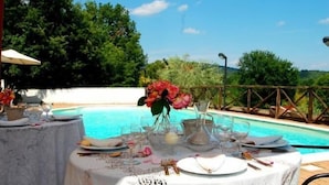 Mesa lista para comer con vista a una piscina y follaje.