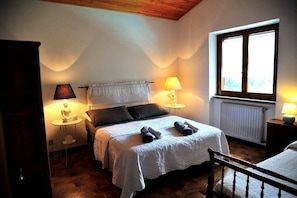 A bedroom with a bed, two bedside lamps, a window, and a radiator. - B&B Il Ciliegio (Manziana)