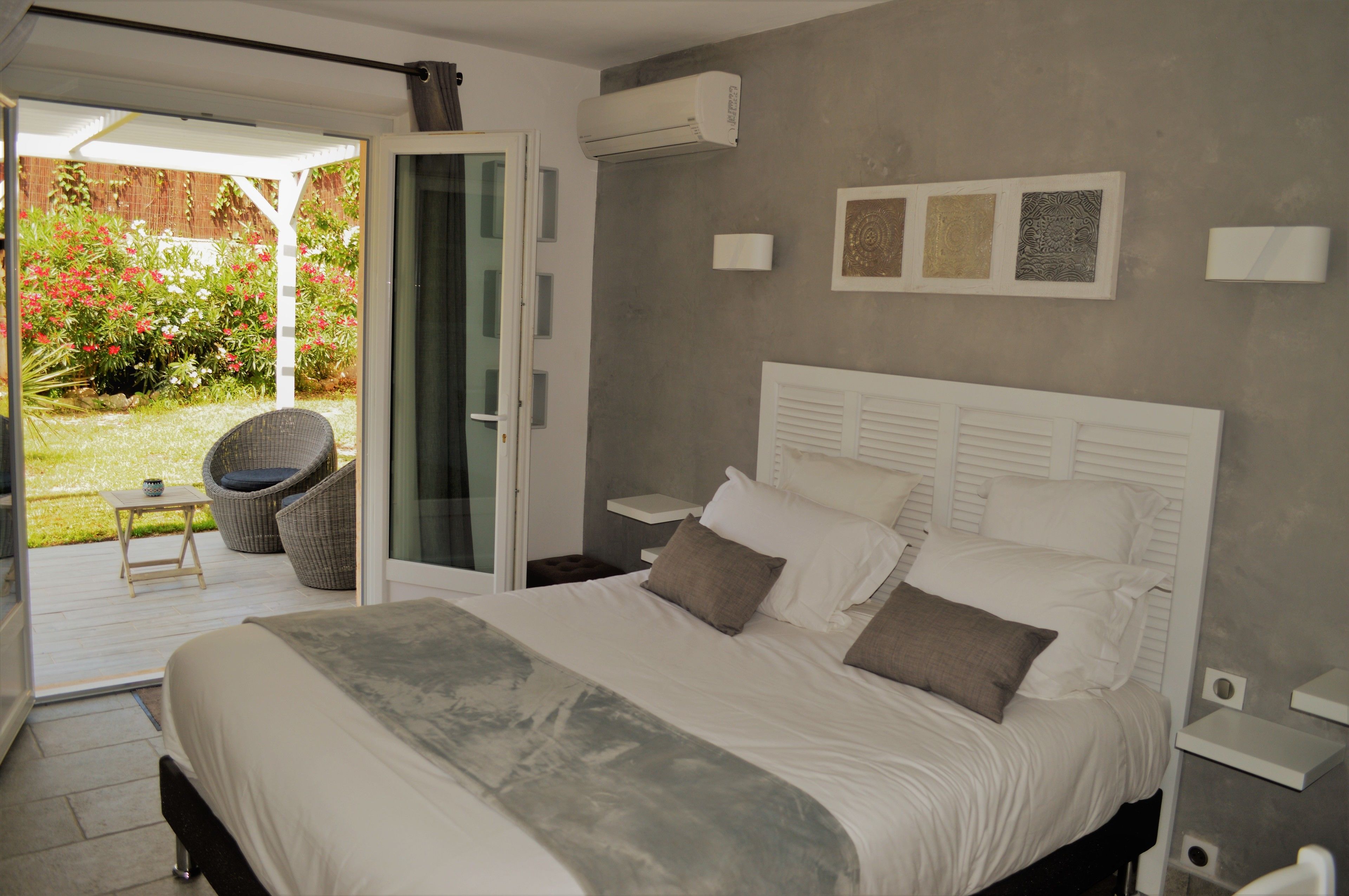 A bedroom with a large bed, a sliding glass door to a patio, and a small table with a chair.