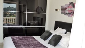 Een slaapkamer met een groot bed, uitzicht door een raam en een balkon.