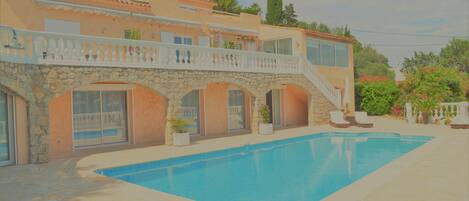 A Mediterranean-style villa with a swimming pool, stone arches, and a balcony overlooking the pool.