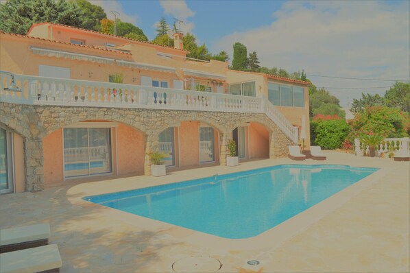 Relax by the pool surrounded by lush greenery and lounge chairs.