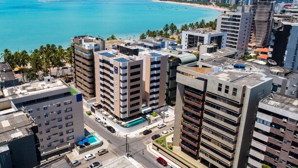 Un hotel de gran altura con varios pisos, piscina en la azotea y vistas a la playa y al océano.