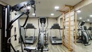 Un gimnasio con diferentes máquinas de ejercicio, una escalera de madera y una pared de azulejos.