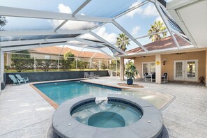 A covered outdoor swimming pool with a hot tub, lounge chairs, and a patio area with a view of the surrounding landscape. - Villa Pearl: 4-bedroom Rental Close To Ocala (Inverness)