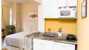Habitación de hotel compacta con cama, kitchenette pequeña y baño.