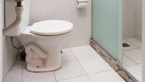 Un baño con inodoro blanco, lavamanos de mármol y cabina de ducha de vidrio.