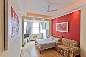 Ein Hotelzimmer mit Bett, Fernseher, Schreibtisch und Computer, sowie einer roten Akzentwand.