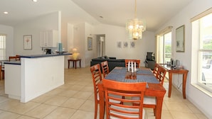 A spacious living area with a dining table, chairs, a sofa, and a kitchen area with a bar counter. - Villa Grandjean - Comfort - 4 Bedroom (Inverness)