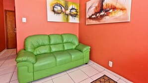 A green leather sofa in a room with red walls and two abstract paintings. - 8th Floor Ocean View - 101D Holiday home 1 (Rio de Janeiro)