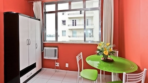 A room with a large window, a white wardrobe, a green table with chairs, and a potted plant. - 8th Floor Ocean View - 101D Holiday home 1 (Rio de Janeiro)