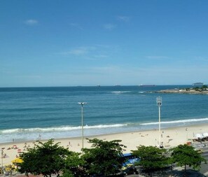Une plage offrant une vue dégagée sur l’océan, un rivage sablonneux et quelques personnes aperçues au loin.
