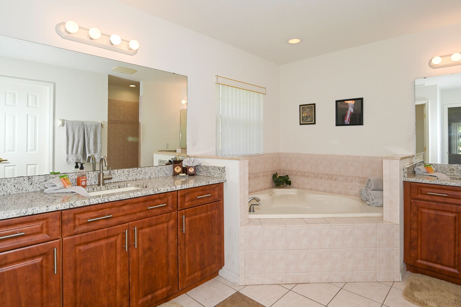 A spacious bathroom with a double sink vanity, a large mirror, a bathtub, and a shower area.
