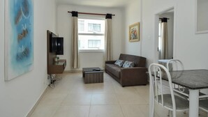Un salon comprenant un canapé, un téléviseur, une table basse et une table à manger avec des chaises.