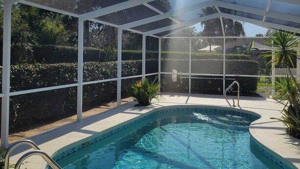 Una piscina interior con techo de cristal, rodeada de plantas y vistas despejadas al exterior.