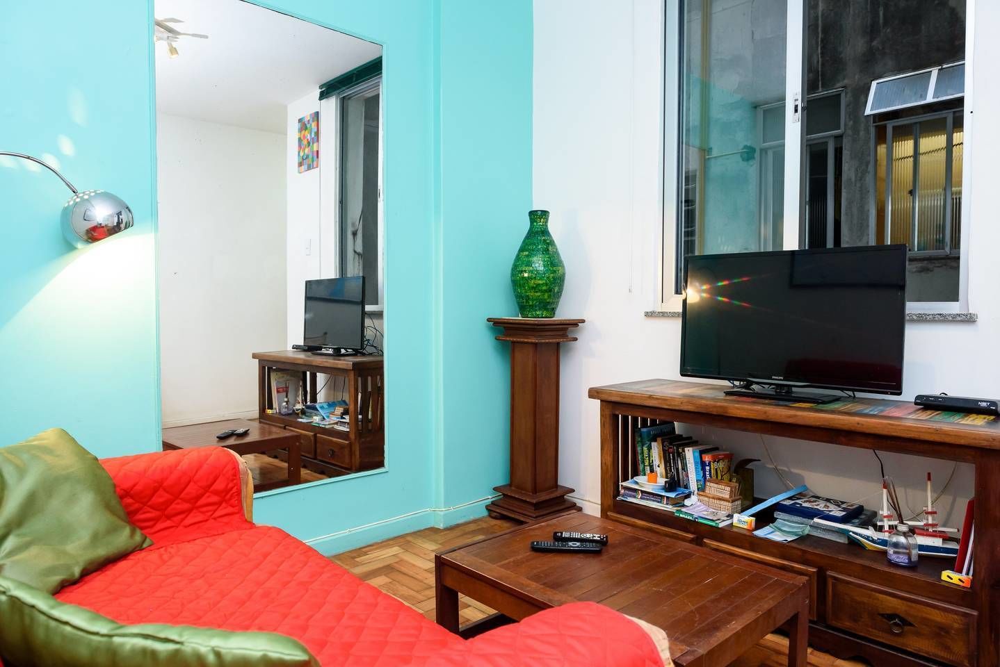 A living room with a red sofa, a wooden coffee table, a TV on a wooden stand, and a bookshelf.