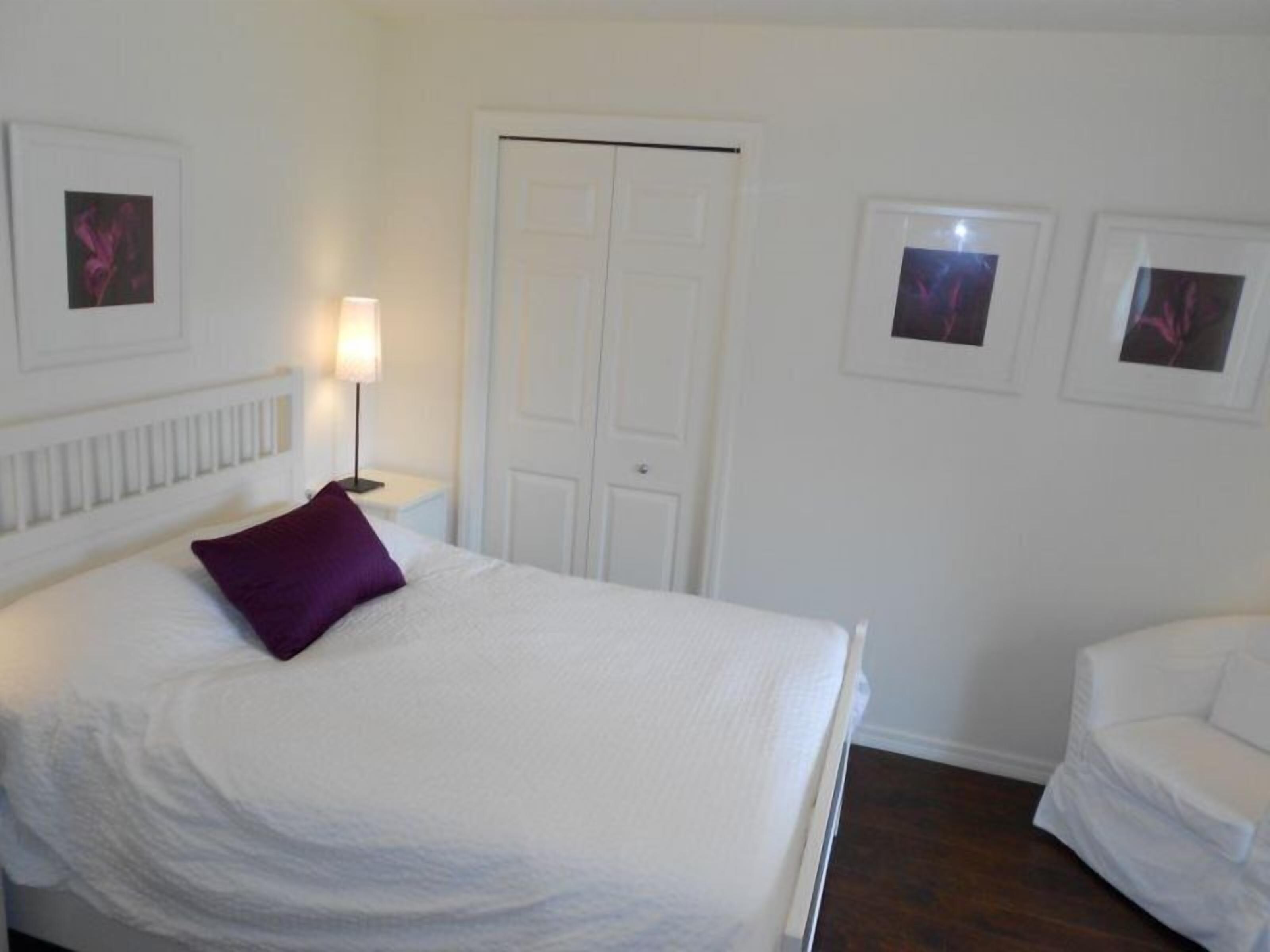 A hotel room with a bed, a nightstand, a chair, and a door.