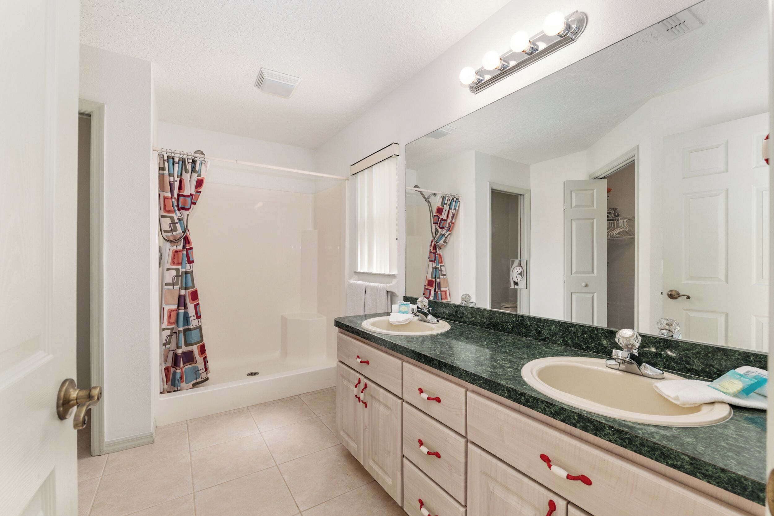 A bathroom with a bathtub, two sinks, a large mirror, and a shower curtain.