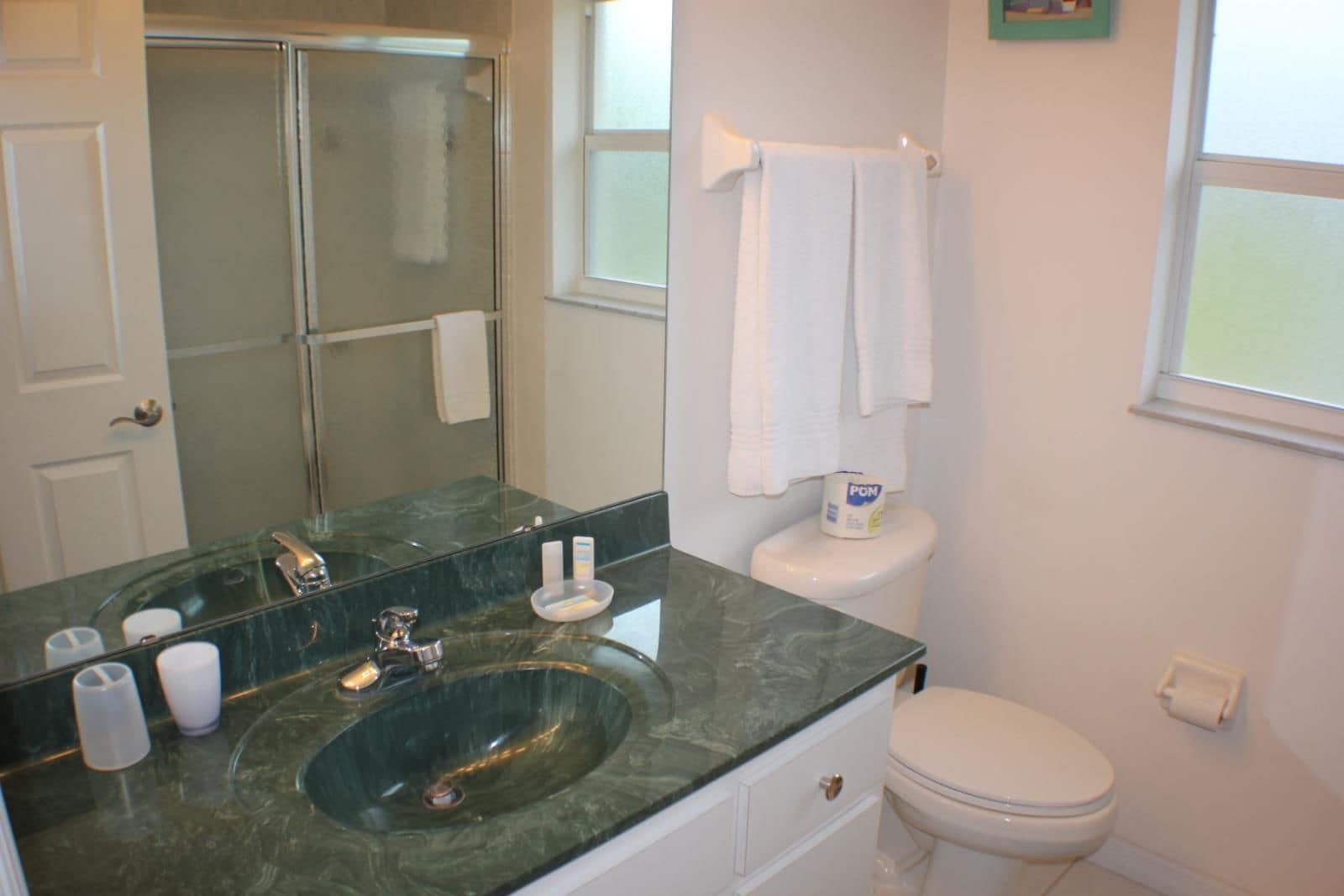 A bathroom with a glass sink, white toilet, and a glass shower enclosure.