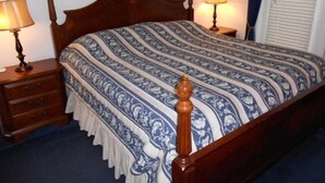 A neatly made bed with a patterned bedspread and two bedside lamps.