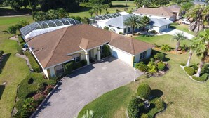 A residential area with multiple houses, each featuring a sloped roof and surrounded by well-maintained lawns and palm trees.