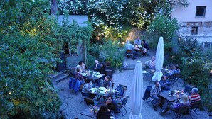 An outdoor patio area with multiple tables and chairs, surrounded by lush greenery and flowering plants. - Nassauer Hof Hotel & Weinwirtschaft (Sankt Goarshausen)
