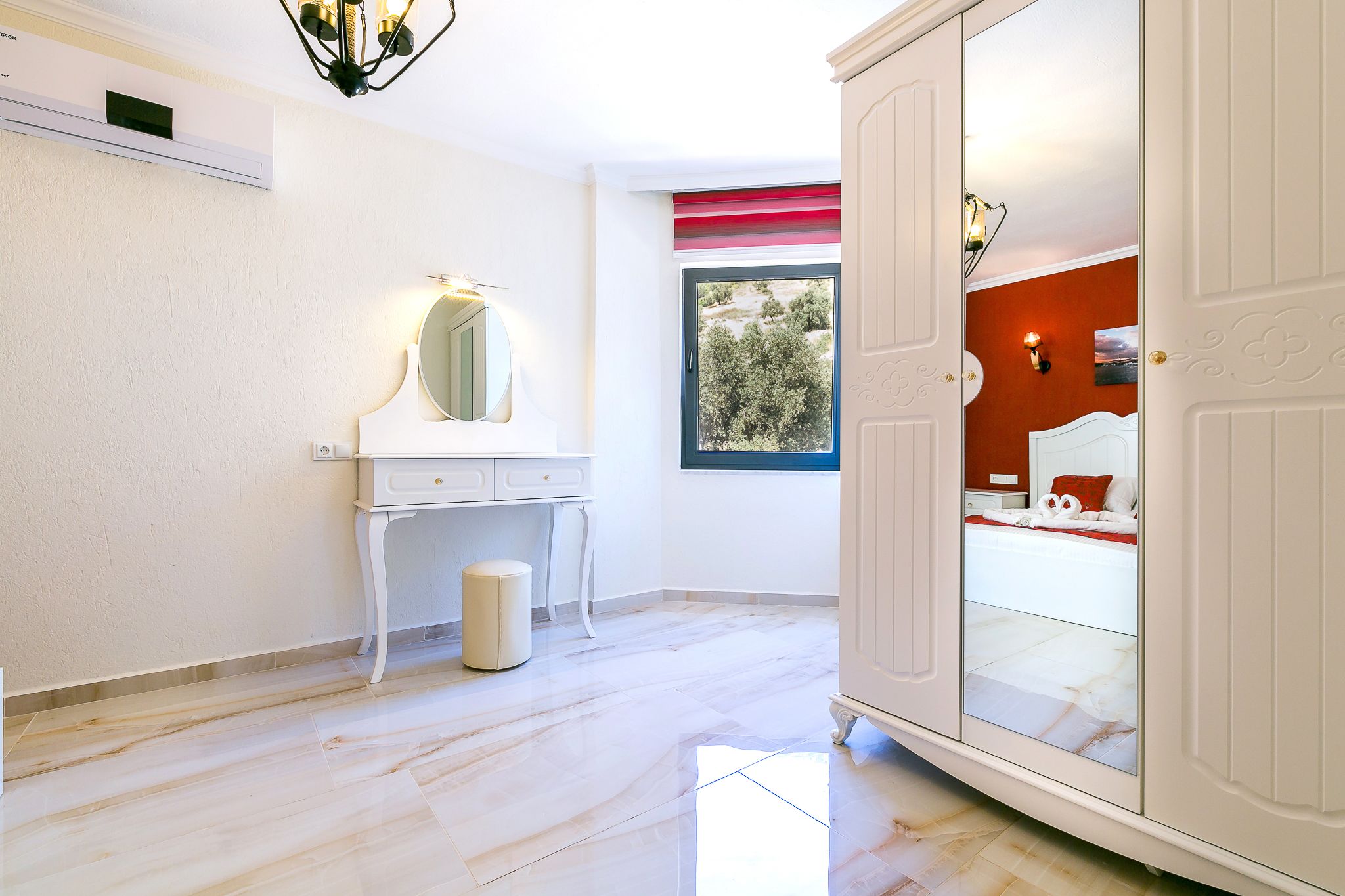 A modern bathroom with a white vanity, a round mirror, and a small trash bin.