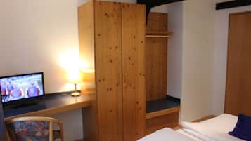 Een kamer met een bed, een bureau met een televisie, een stoel en een kledingkast.