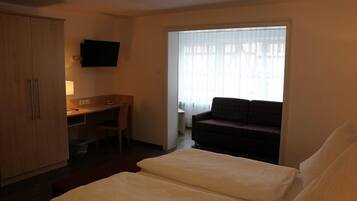 Ein Hotelzimmer mit Bett, Schreibtisch, Stuhl, Fernseher und einem fensterbepflanzten Fenster.