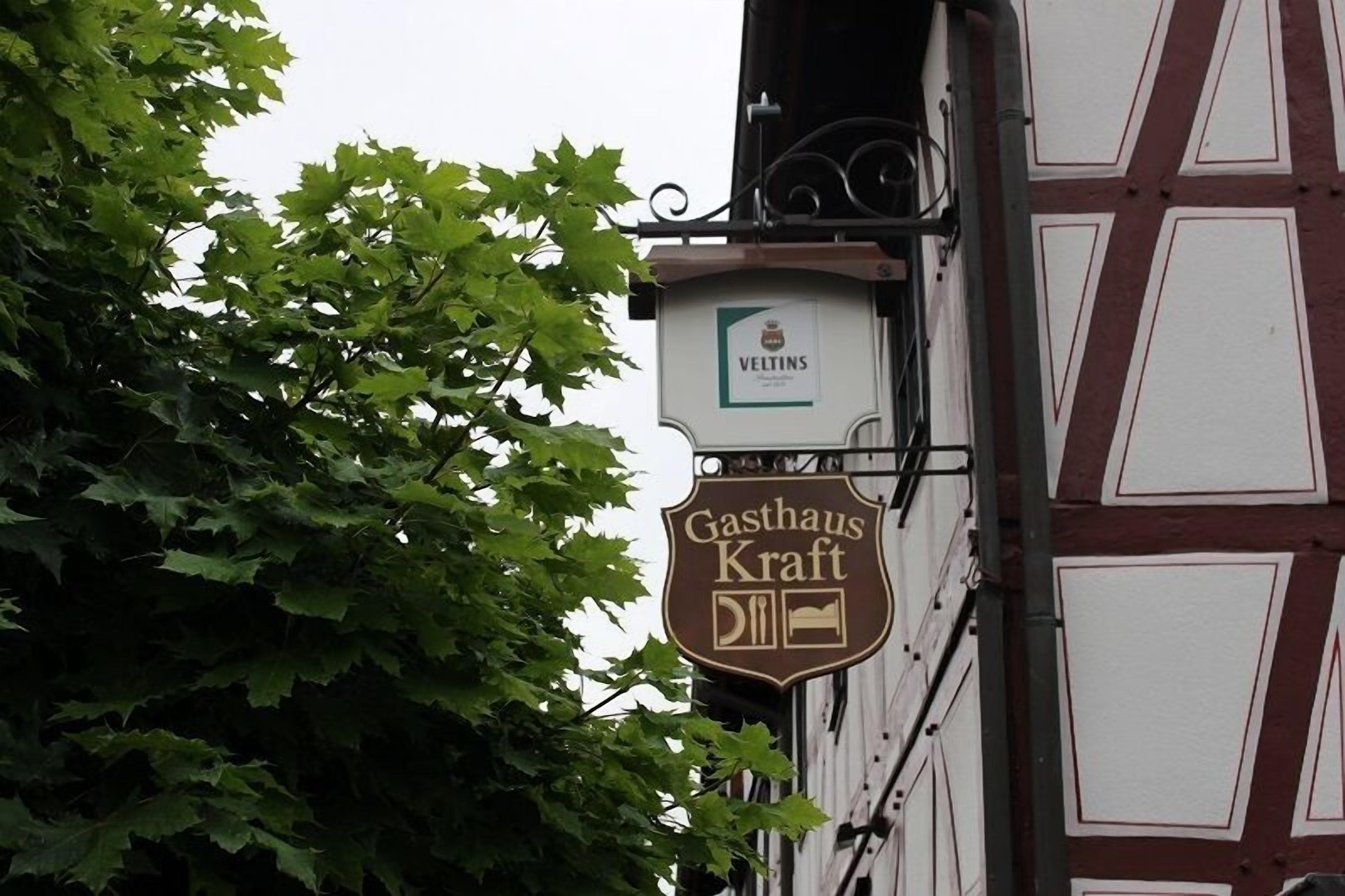 A building with a sign for 'Gastrhaus Kraft' and a 'VELTINS' sign above it.
