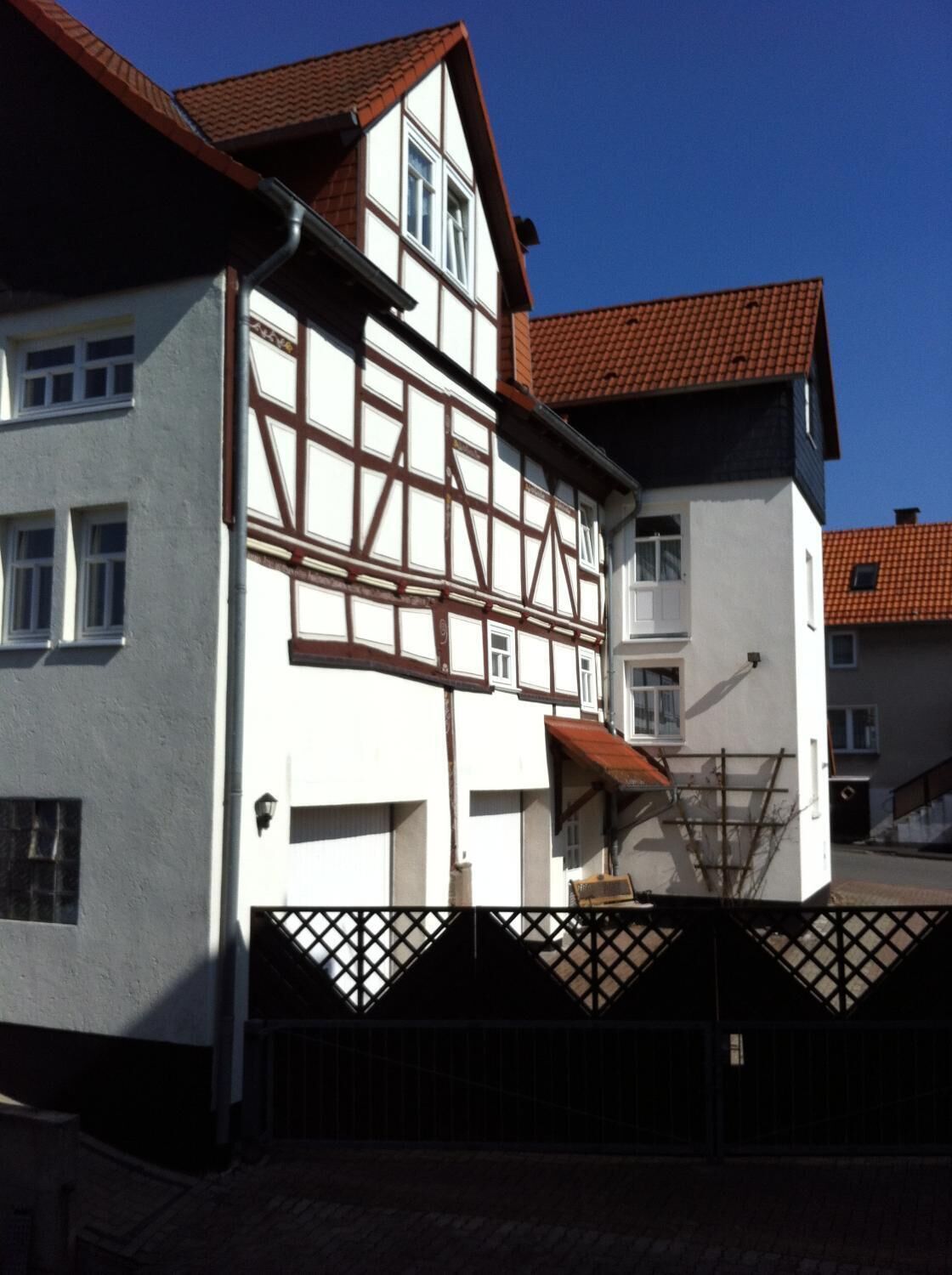 Ein traditionelles Fachwerkhäuschen mit rotem Ziegeldach, einem verschlossenen Eingang und blauem Himmel im Hintergrund.