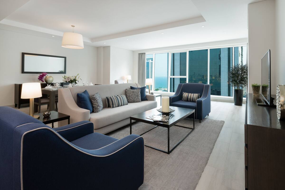 Una sala de estar moderna con un sofá, sillones, una mesa de centro y un televisor.