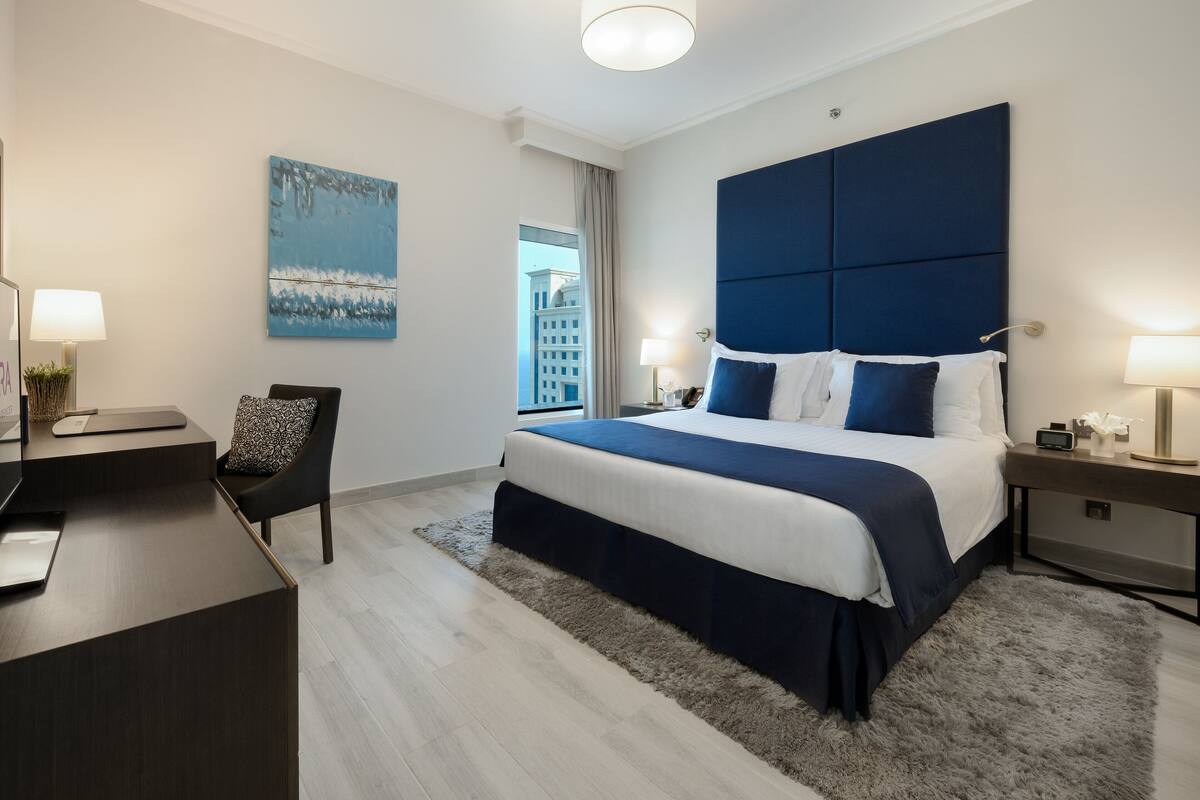 Una habitación de hotel moderna con una cama grande, un escritorio y una silla.