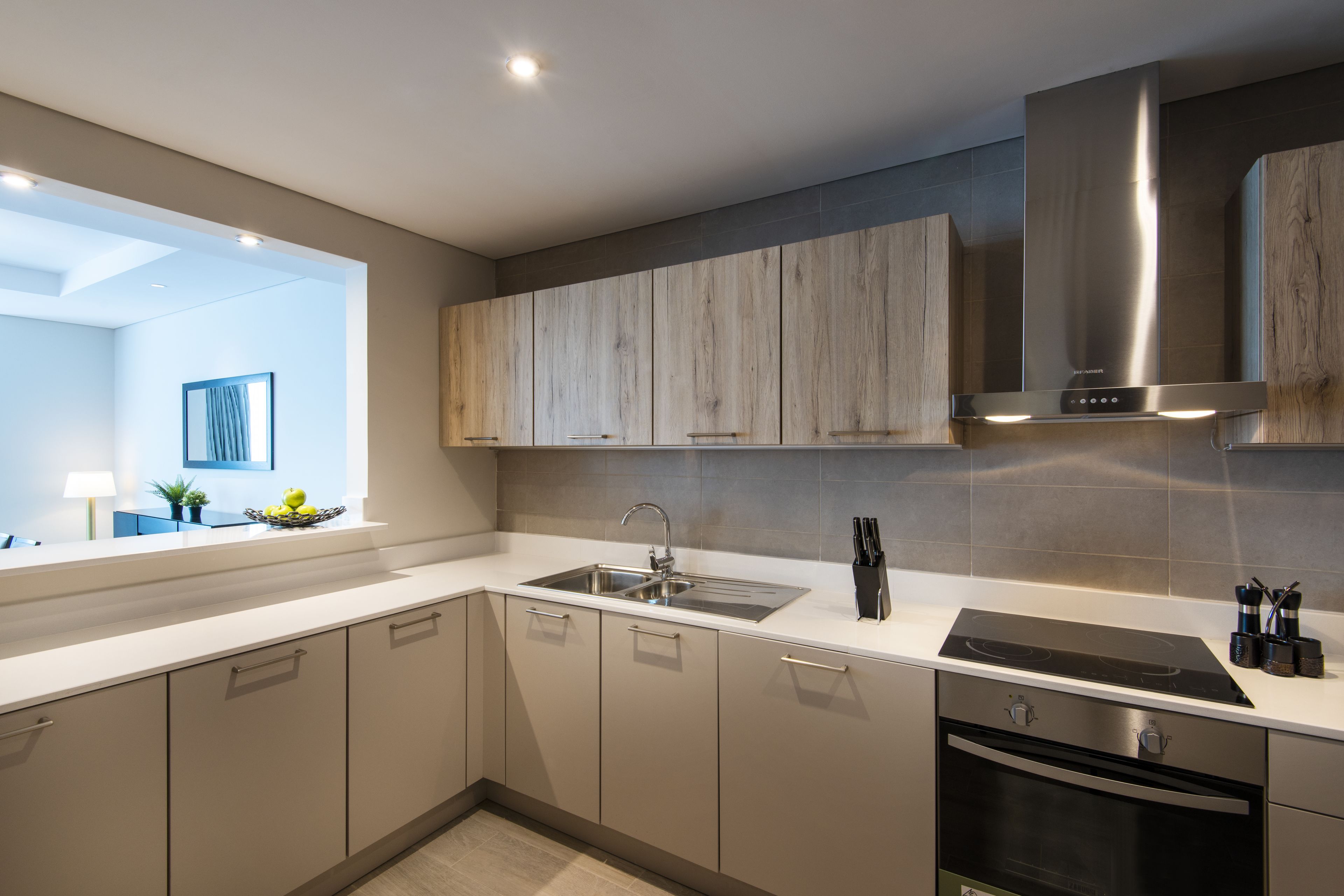A modern kitchen with a built-in oven, stainless steel sink, and wooden cabinets.