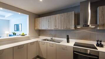 A modern kitchen with a built-in oven, stainless steel sink, and wooden cabinets.