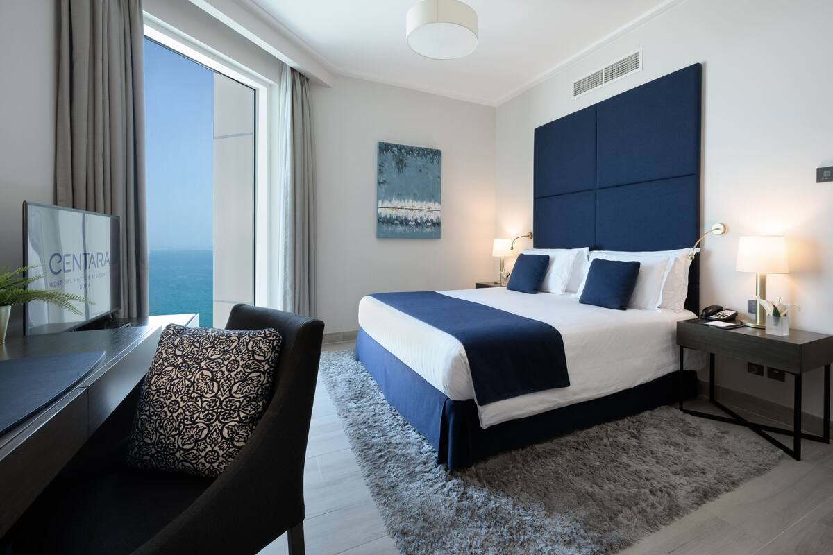 Una habitación de hotel moderna con una cama grande, un escritorio y vista al mar.