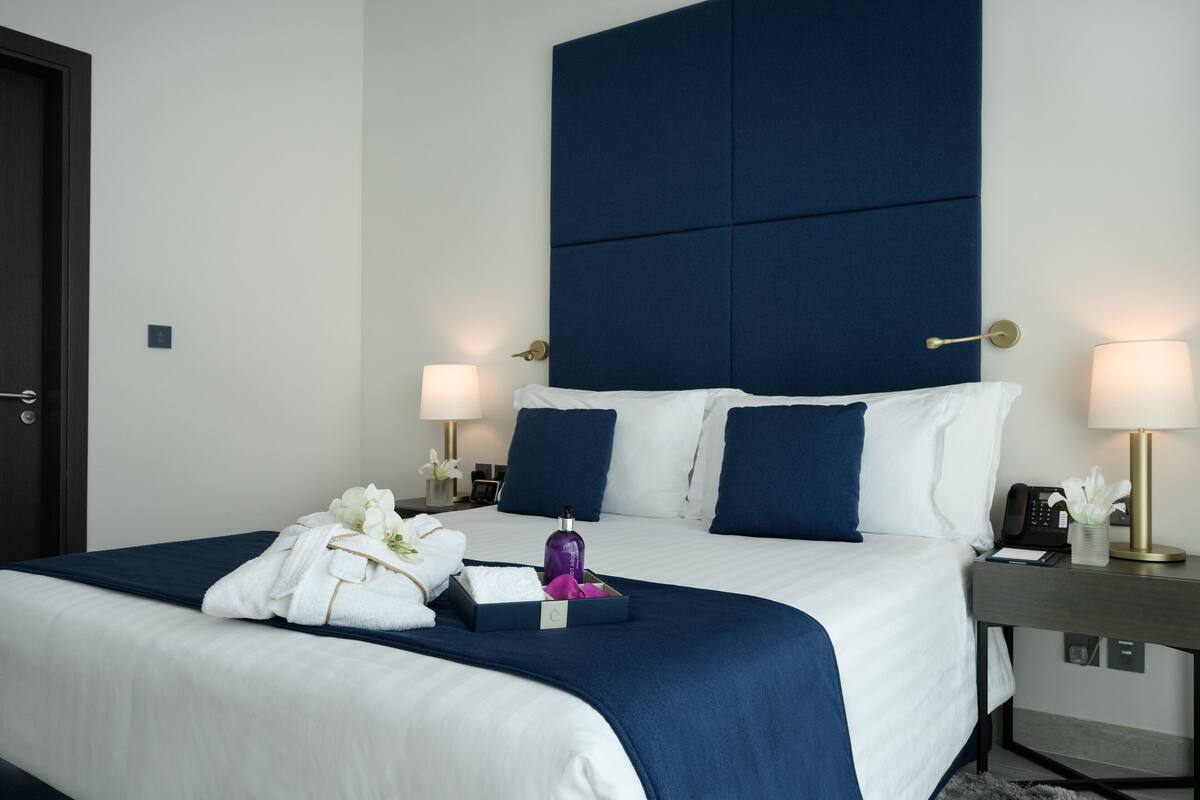Habitación de hotel con una cama grande, dos mesitas de noche y un teléfono instalado en la pared.