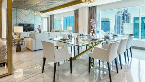 Un comedor moderno con una mesa de vidrio, sillas blancas y vistas a la ciudad.
