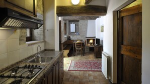 A kitchen with a gas stove, sink, and wooden ceiling beams.