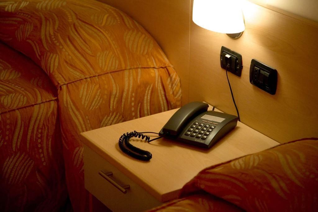 Une chambre d’hôtel équipée d’une table de chevet, d’un téléphone et d’une prise électrique murale.