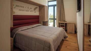 Ein Schlafzimmer mit einem großen Bett, einem Holz-Kopfteil, einem kleinen Schreibtisch und einem Fenster mit Vorhängen.