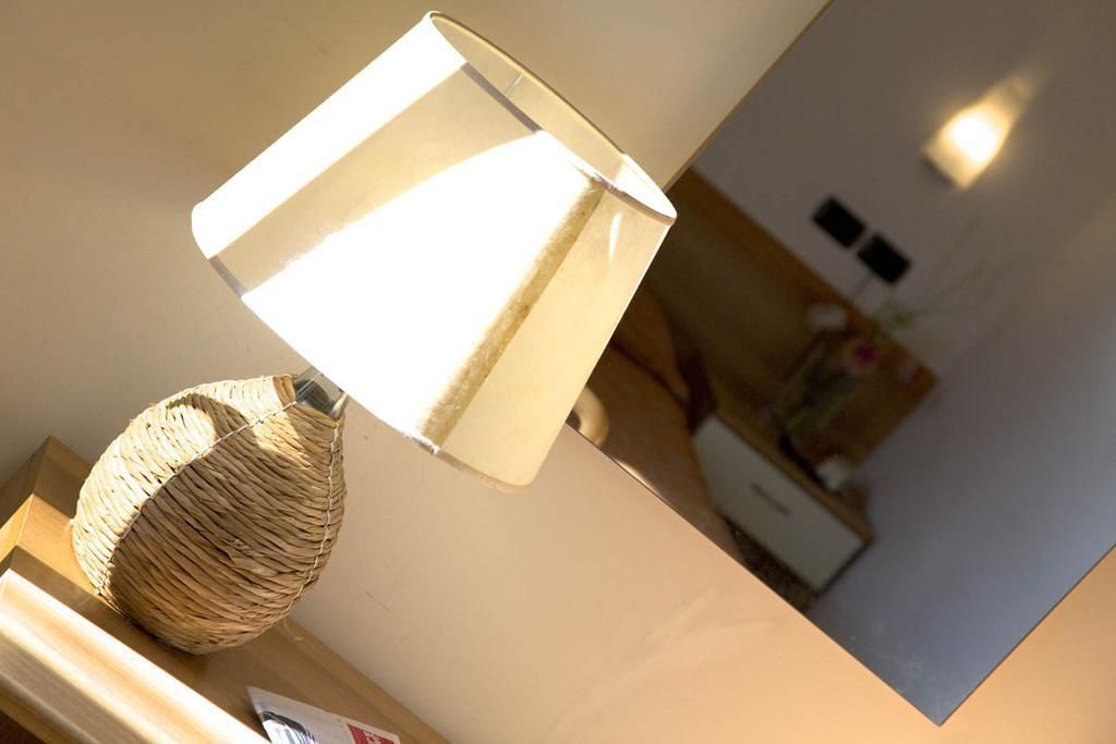 Eine Lampe mit geflochtenem Fuß und einem weißen Schirm auf einer Holzoberfläche.