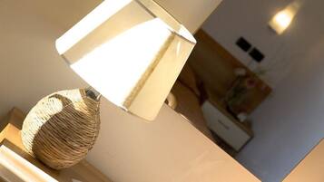 Eine Lampe mit geflochtenem Fuß und einem weißen Schirm auf einer Holzoberfläche.