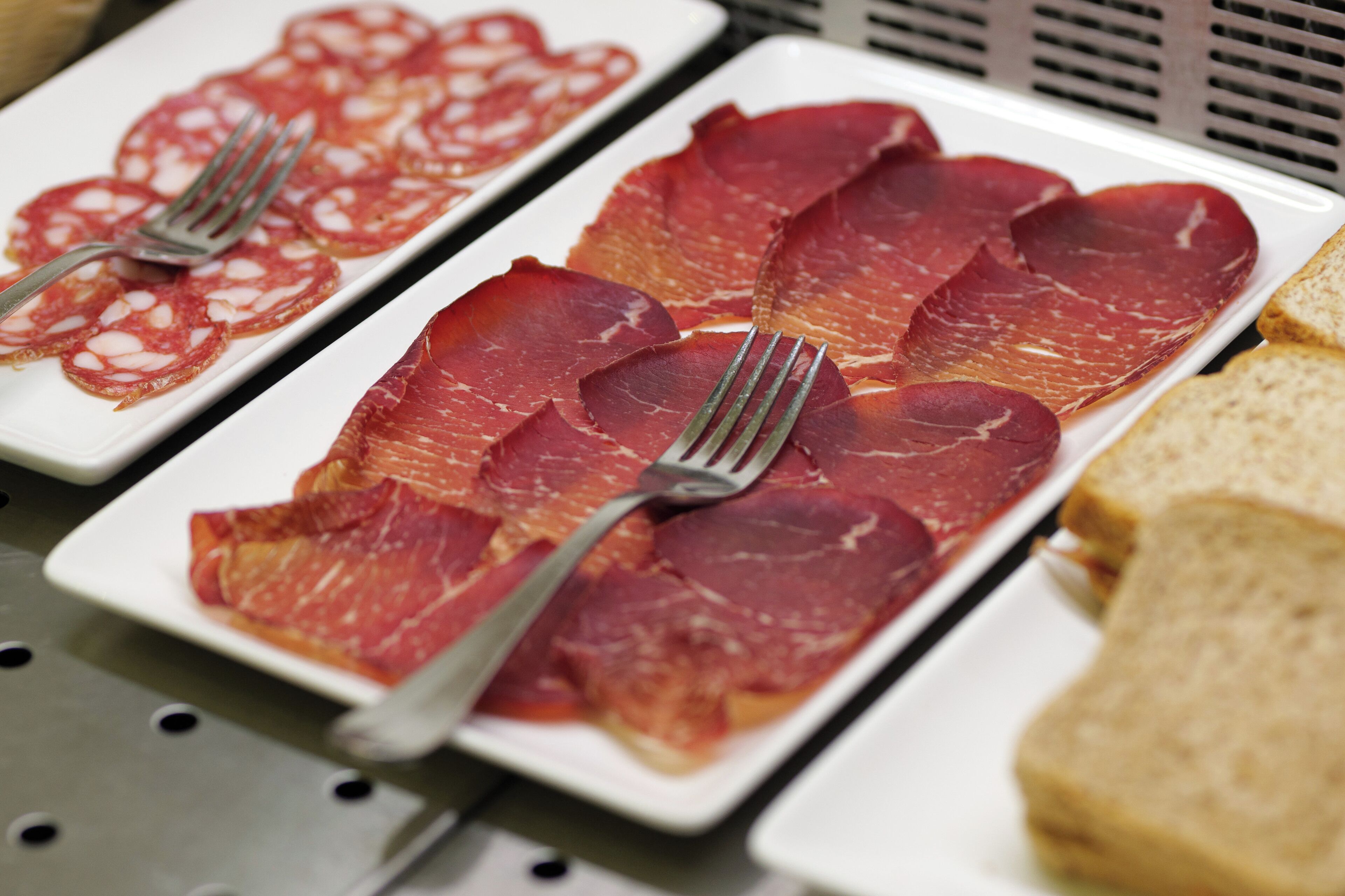 A buffet with sliced meats and bread.